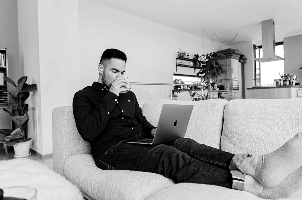 Jeune homme sur son canapé devant son ordinateur laptop