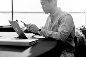Jeune homme asiatique avec son téléphone intelligent et ordinateur portable laptop travail solopreneur