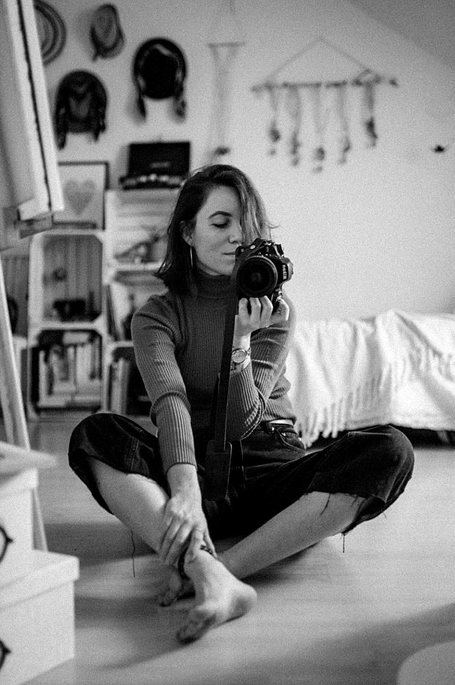 Jeune femme photographe dans sa chambre avec son appareil photo