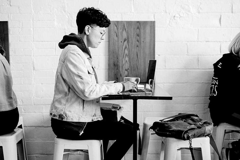 Jeune personne non genrée devant son ordinateur portable laptop travailleur autonome graphiste